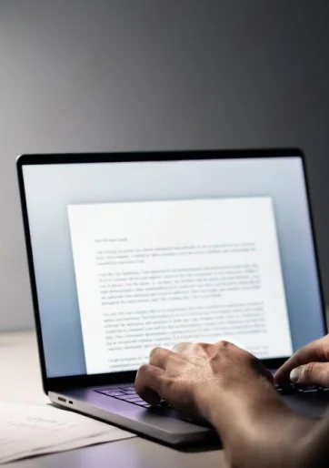 Close-up of a copywriter's hands typing website copy on a laptop keyboard.